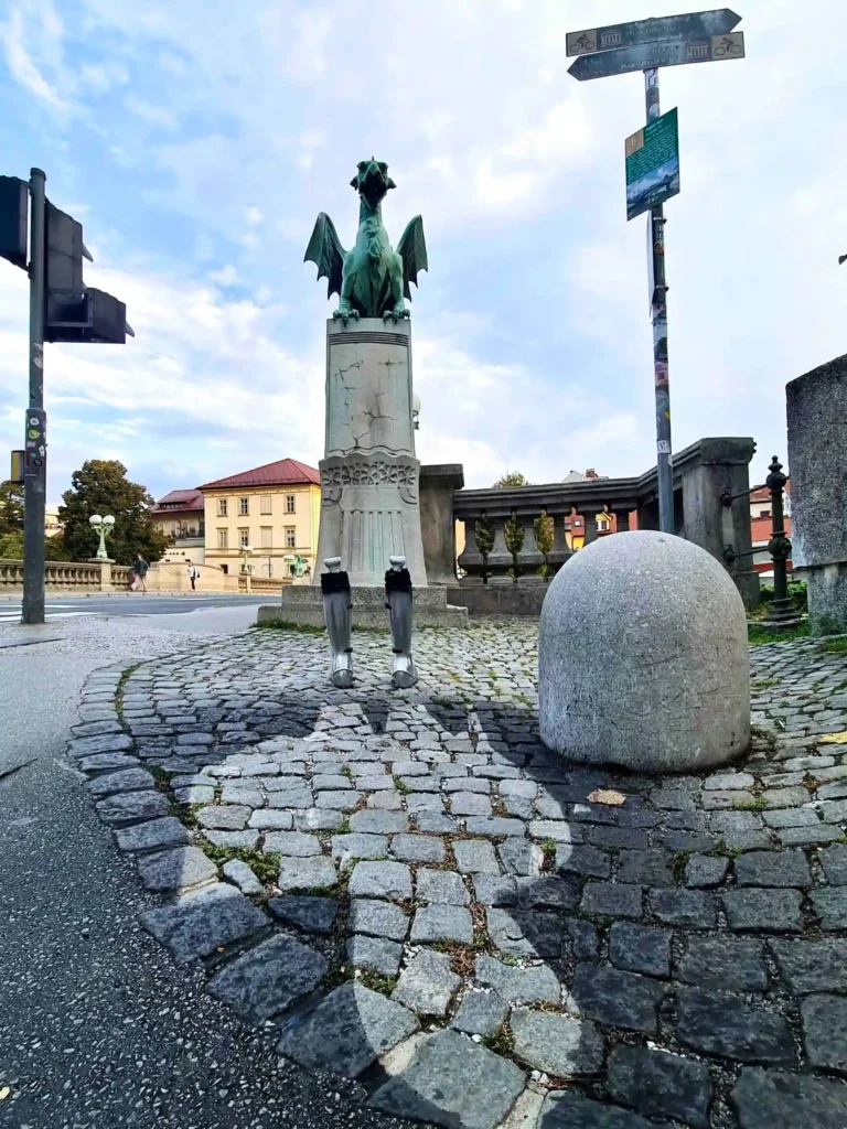 Full view of the artistic installation featuring a dragon statue, medieval knight's boots, and the silhouette of a burned figure on the ground.