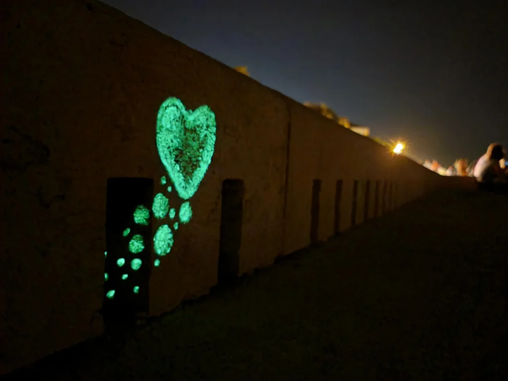 Close-up image of the sea organ featuring a bubble-style painted heart and glowing bubbles emerging from a hole, captured at night to showcase the luminous paint.