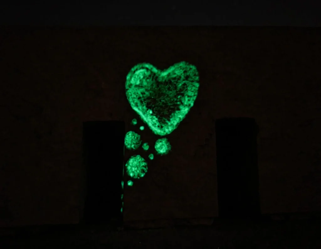 Close-up image in front of the sea organ featuring a bubble-style painted heart and glowing bubbles emerging from a hole, captured at night to showcase the luminous paint.