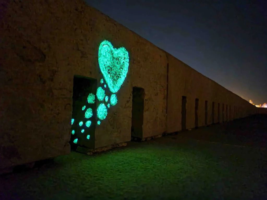 Close-up image of the sea organ featuring a bubble-style painted heart and glowing bubbles emerging from a hole, captured at night to showcase the luminous paint.