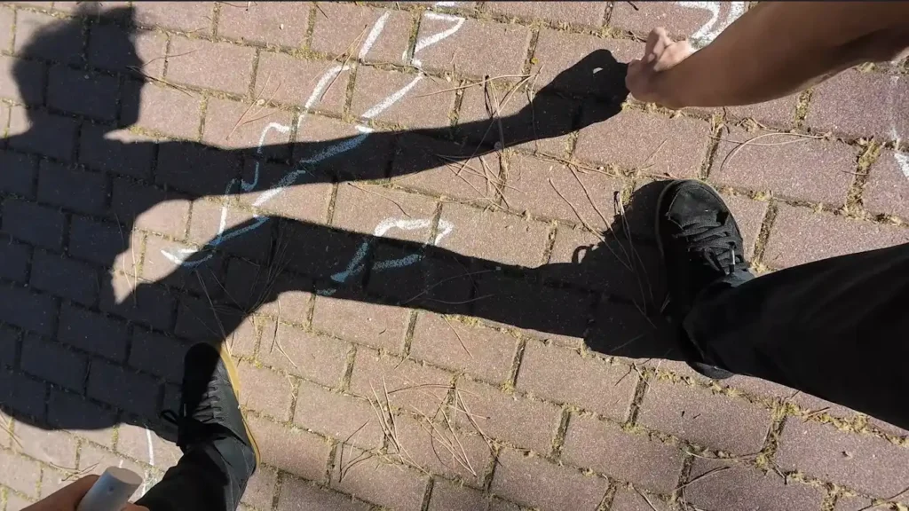 Shadow silhouette of a person drawing with chalk on the ground of the street