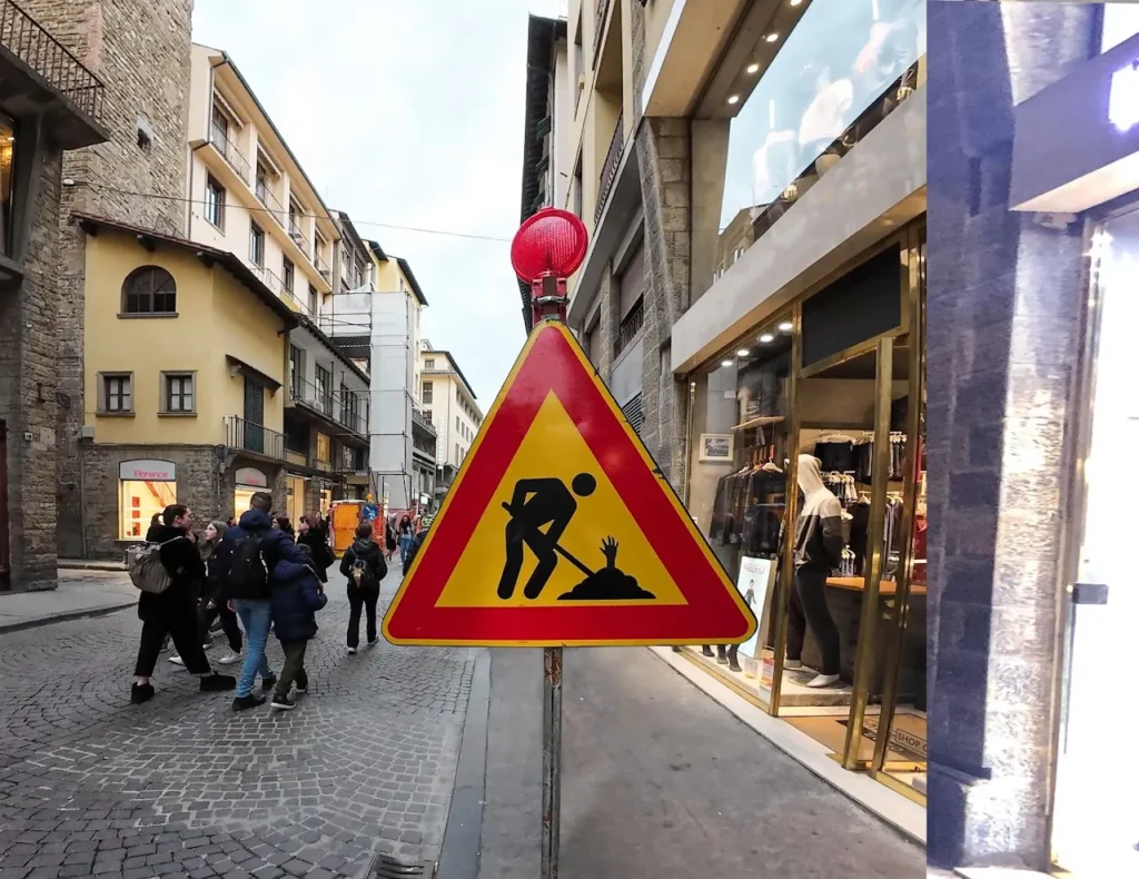 To the left of the image, a business district stands out, extending with glass buildings rising towards the sky. To the right, a peculiar sculpture catches the eye: a slice of pizza adorned with slices of ham, each marked with the symbol of a euro bill, piercing the wooden door of a street library. This visual representation evokes the idea of social equality in the everyday experience of eating, a notion present in various cultures.