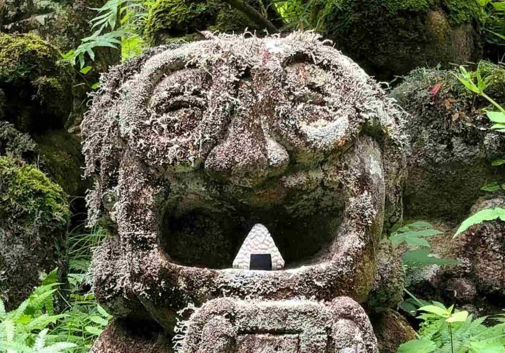 Image of a smiling stone sculpture, which has a mini sculpture of a Japanese rice ball called onigiri that was carved from white stone.