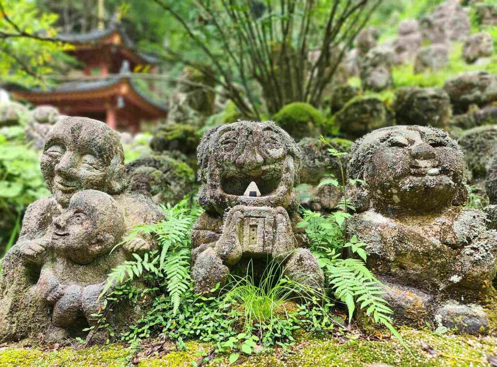 Image of a smiling stone sculpture, which has a mini sculpture of a Japanese rice ball called onigiri that was carved from white stone.