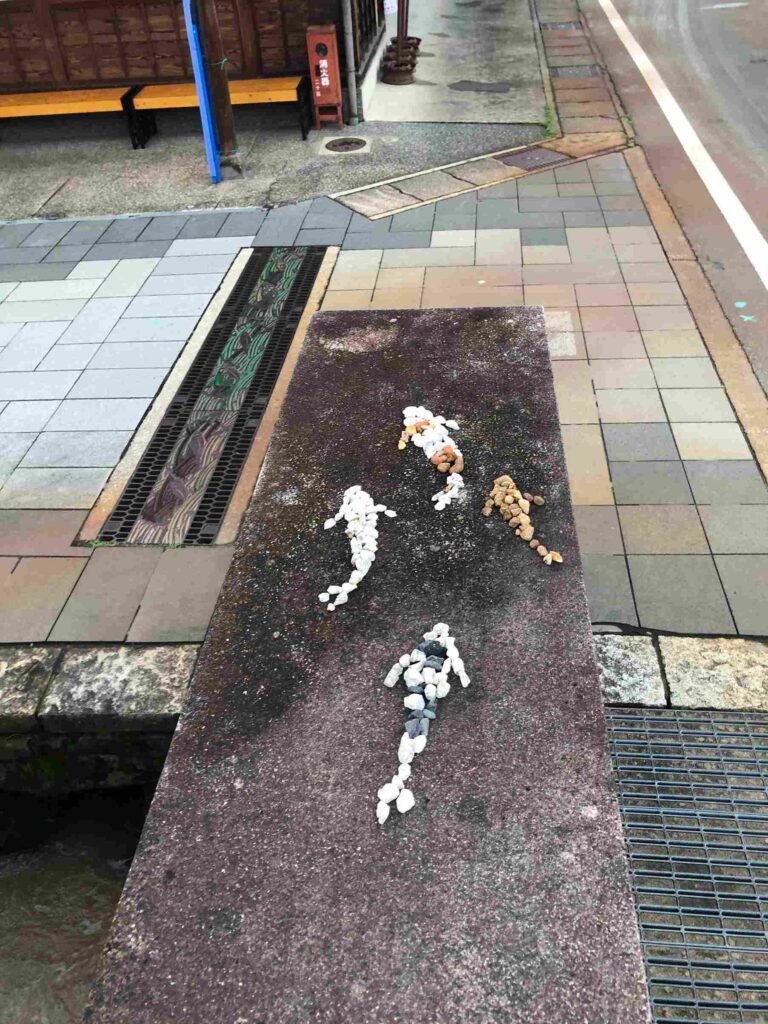 Image of three koi fish created with colored river stones that are placed in the shape of koi fish swimming.