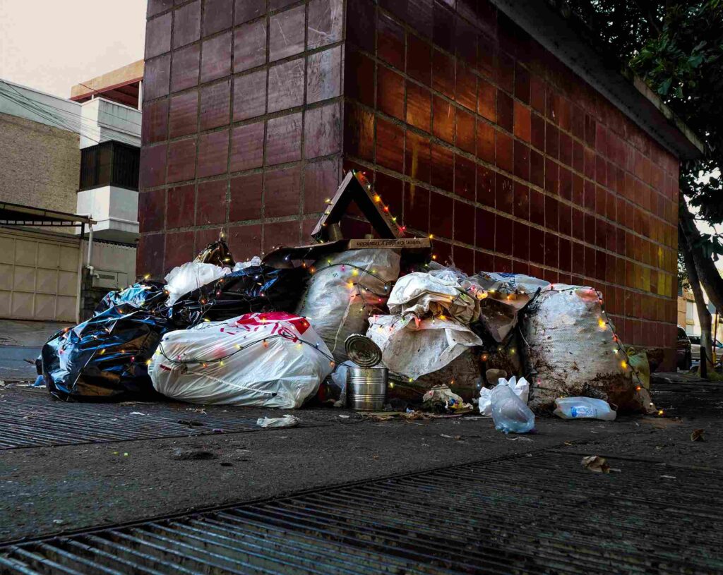 Nativity scene created with garbage bags and other street waste, decorated with Christmas lights.