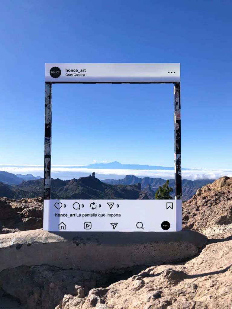 A viewpoint on the mountaintop of Gran Canaria island, located in Spain, where the entire panorama can be appreciated, some strips of white paper are placed on a rectangular metal arch that was already in place, simulating the frame of social media posts, with the legend: The screen that matters.