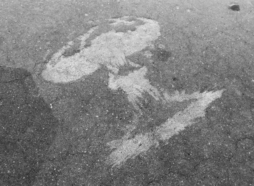 Water balloon bursting on the concrete ground, forming a puddle shaped like a nuclear explosion