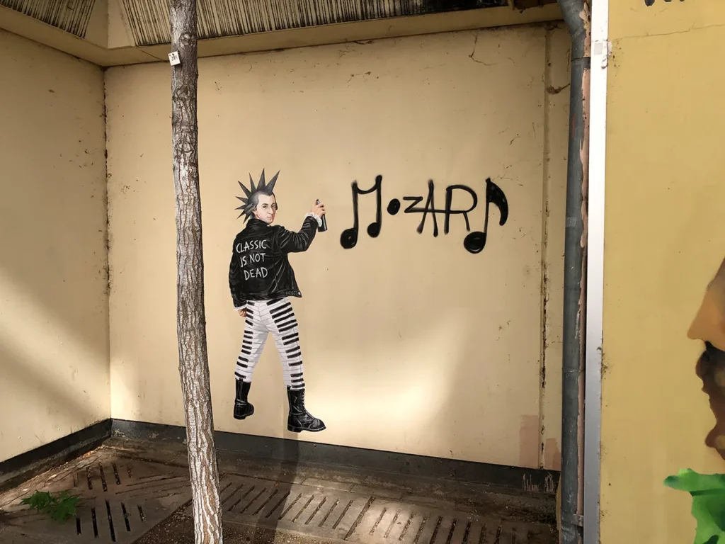 Painting of Mozart with a punk hairstyle in a leather jacket reading 'Classics is not dead', trousers with a piano key print and military boots, painting a musical note graffiti