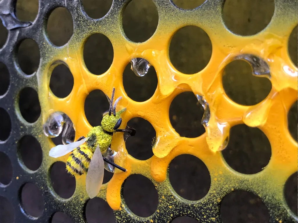 Handmade bee figure made from leaves and twigs on a window screen simulating a honeycomb