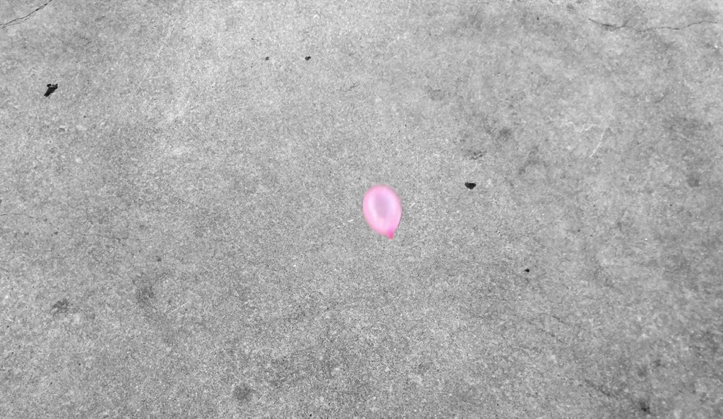 Close-up of a pink water balloon about to impact the concrete